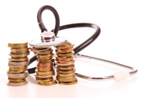 Coins stacked next to a stethoscope