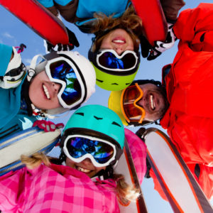 Family wearing ski goggles smiling at the camera