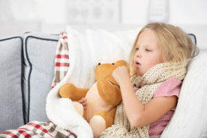 girl coughing with a teddy bear