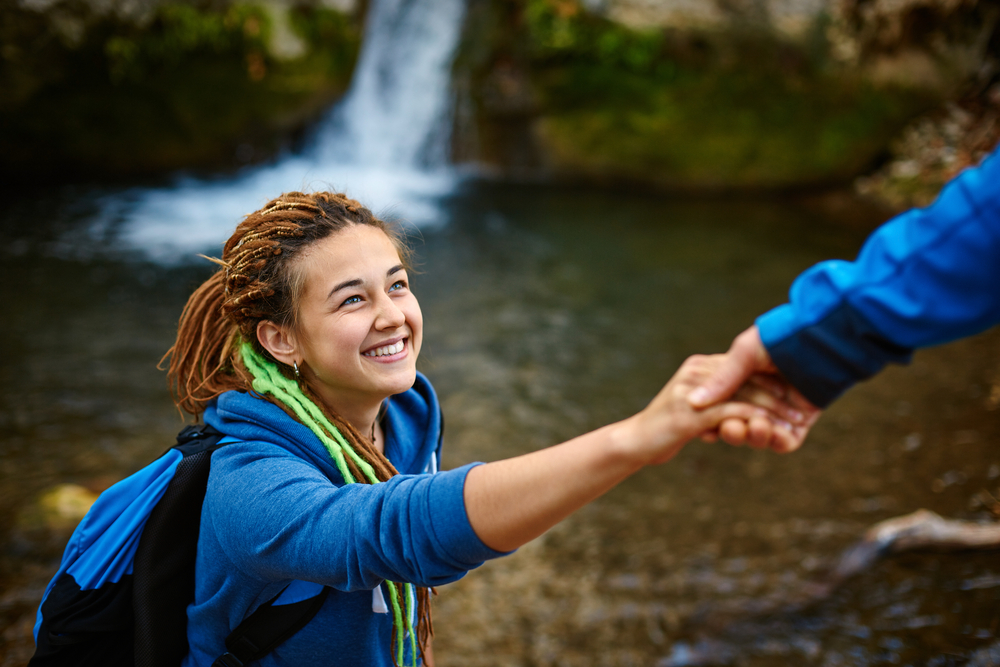 girl smiles as she receives help as she is hiking