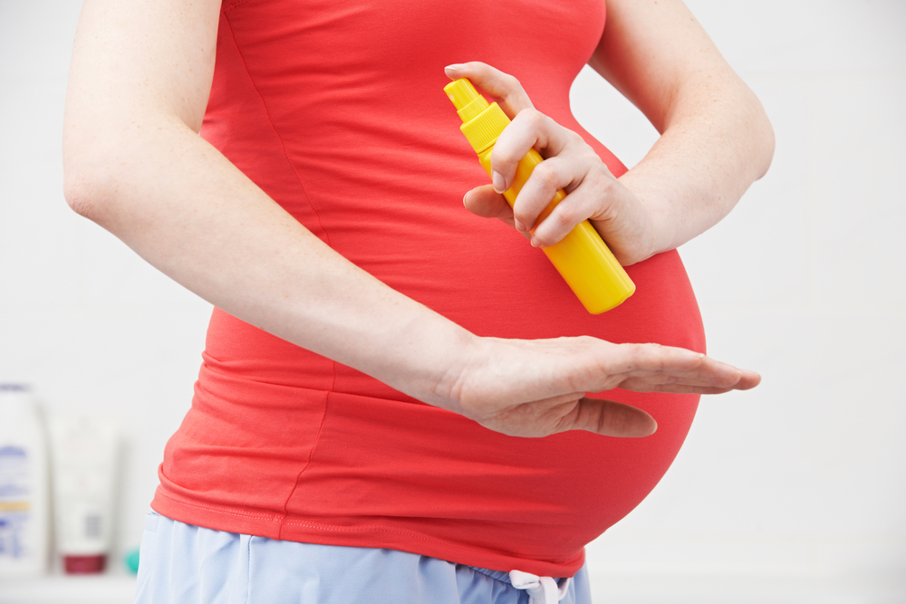 Photo of pregnant woman using bug spray