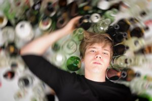 Photo of boy with alcohol bottles.