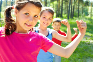 Children outdoors flexing muscles