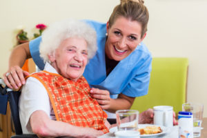 senior and nurse with lunch smiling