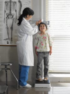 Doctor measuring girl (5-7 years) in examination room