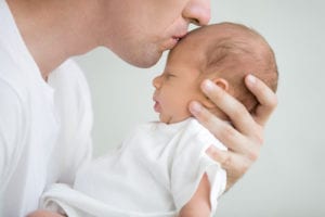 Photo of dad kissing newborn