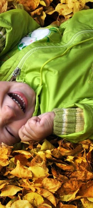 little boy in fall leaf pile