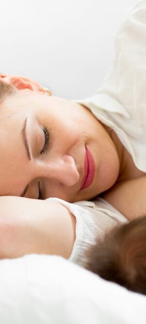 mom breastfeeding newborn on bed