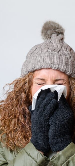 woman in coat blowing nose