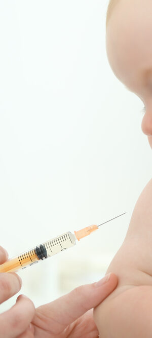 baby looking at vaccine syringe