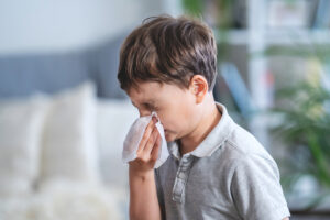 boy blowing nose with tissue