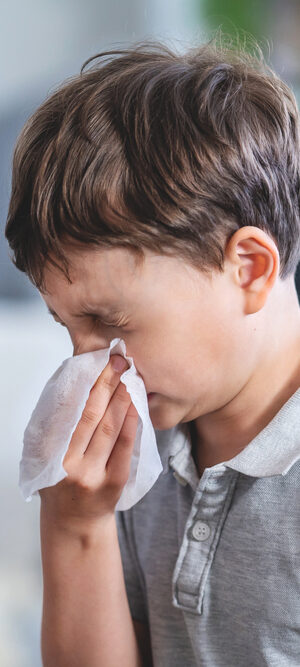 boy blowing nose with tissue