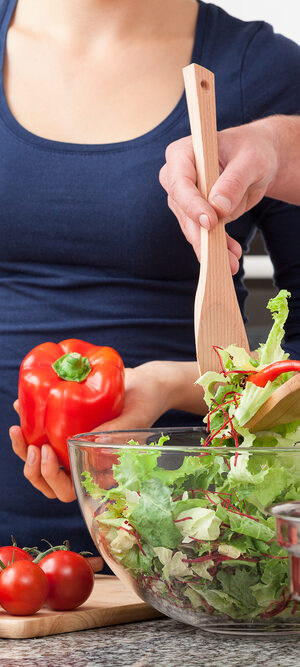 couple making salad in kitchen