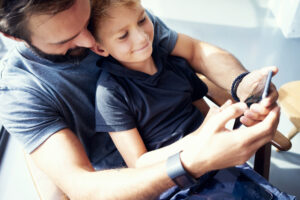 dad on son with smartphone