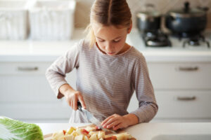 girl cutting food in kitchen
