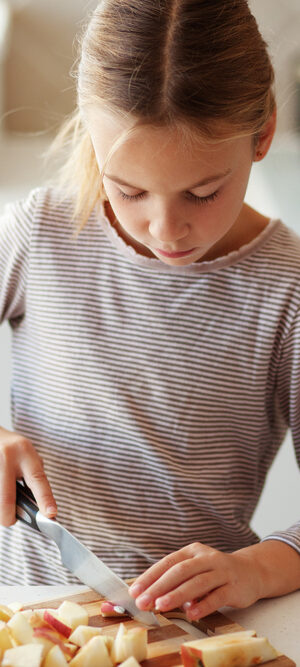 girl cutting food in kitchen