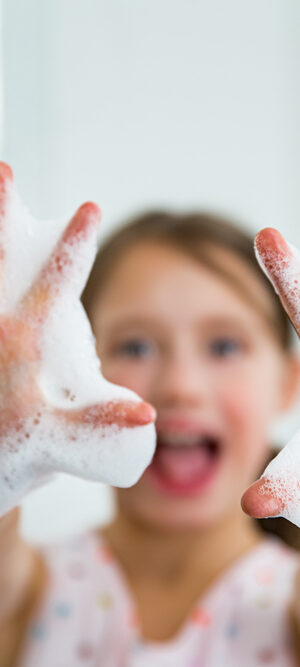 girl holding up soapy hands