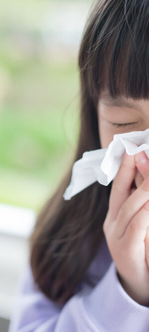girl sneeses into tissue