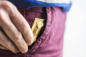 hand putting condom in pocket