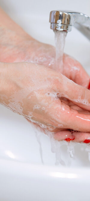 hands with red polish getting washed