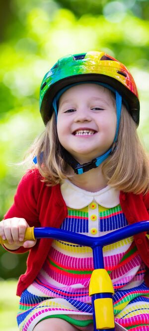 little girl riding bike outdoors in colorful clothes