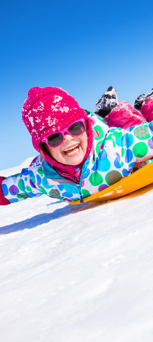 little girl sledding on snow