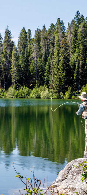 man fly fishing on clear lake