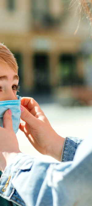 mom helping boy with face covering