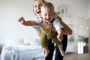 mom holding toddler and laughing