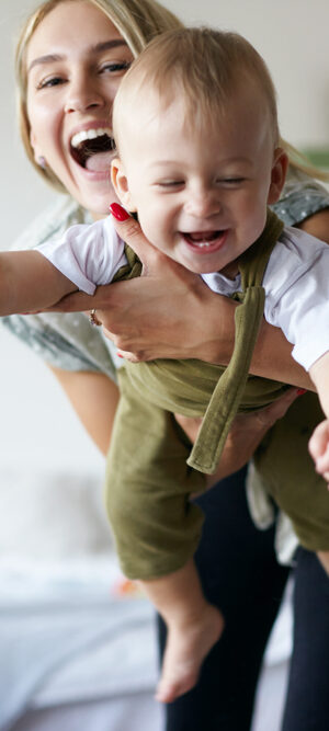 mom holding toddler and laughing