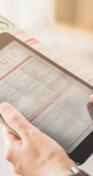 news on tablet with newspaper