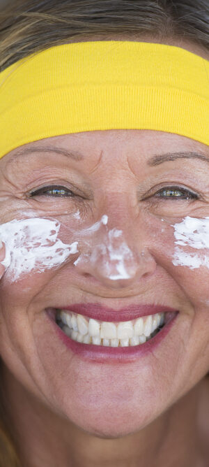 older woman putting on sunscreen