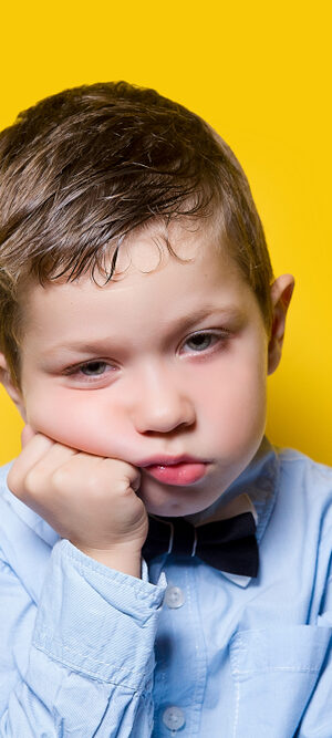 sad boy with a bowtie on yellow