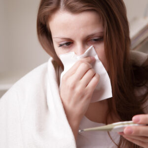 sick woman with tissue and thermometer