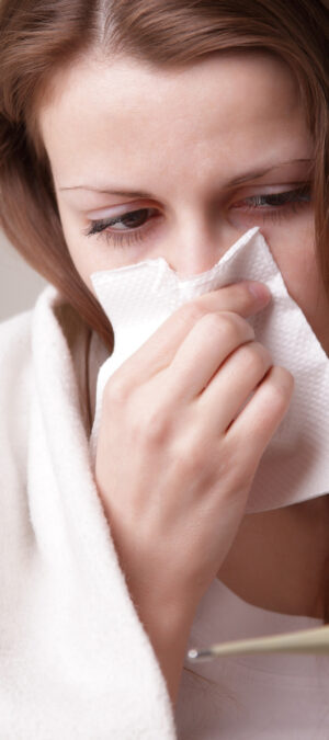 sick woman with tissue and thermometer