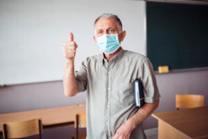 teacher with face covering and thumbs up