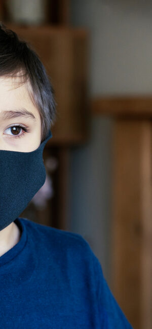 young boy wearing black face covering