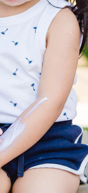 young girl putting on sunscreen