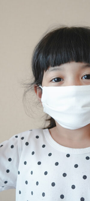 young girl with face covering and thumbs up