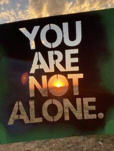 Stencil in the sunset with the phrase "You are not alone."