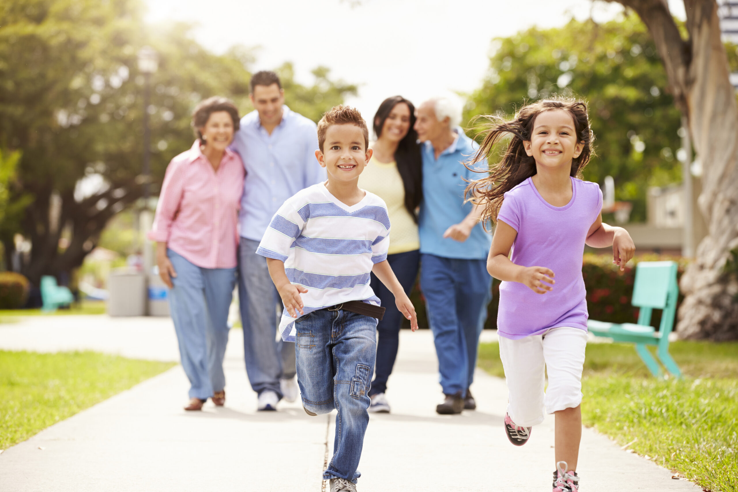 multigenerational family walks and runs on a sidewalk